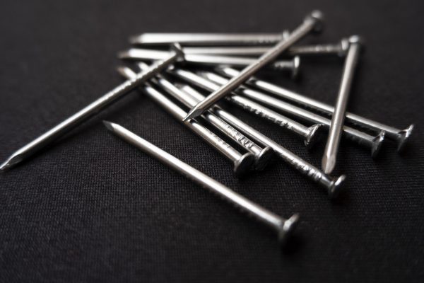 A closeup shot of some steel nails on a black surface