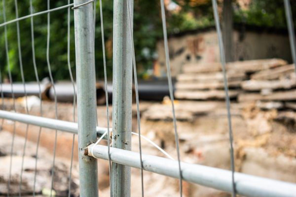 Selective focus of fence around trench with insulated water pipes and concrete slabs outdoors. Urban sewerage infrastructure concept, modernization and reconstruction of underground system.